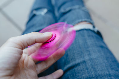 Midsection of person spinning pink fidget spinner