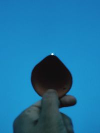 Low angle view of human hand against blue sky