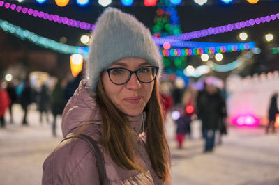 Portrait of young woman in city at night