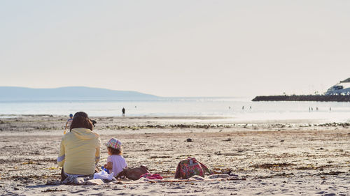 Rear view of people sitting on beach