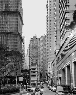 Traffic on road amidst buildings against clear sky