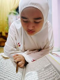 Close-up of girl reading koran