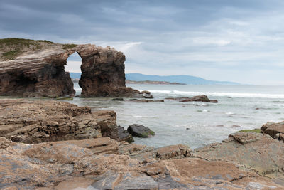 Rock formation on beach against sky