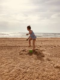 Full length of girl playing at beach against sky