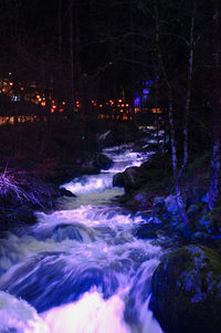 River flowing in illuminated city at night