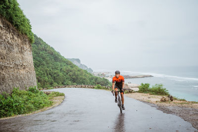 Rear view of man riding bicycle on road against sky