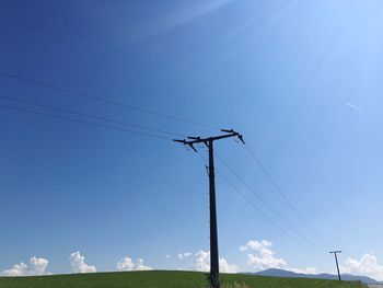 Low angle view of power line against blue sky on sunny day