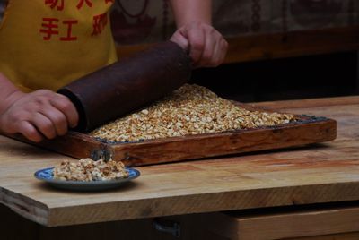 Midsection of chef crushing caramel on wood at street market stall