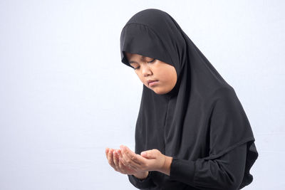 Girl in hijab praying over white background