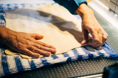 Close up of human hand prepairing dough on table