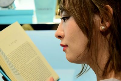 Close-up portrait of young woman reading book