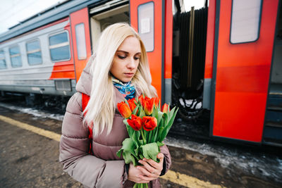 Sad girl on the station platform with flowers near the train