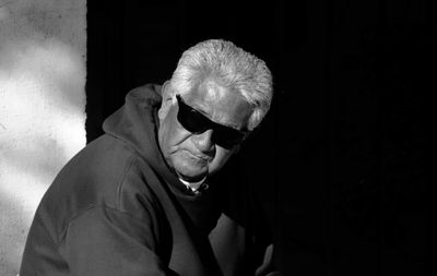 Portrait of man holding ice cream against black background