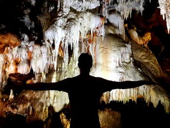 Rear view of silhouette woman in cave