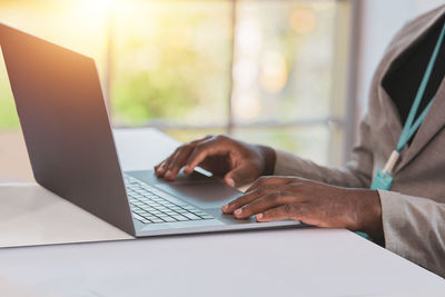 Midsection of man using laptop at table