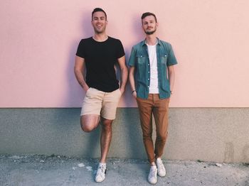 Full length of two men leaning on exterior wall
