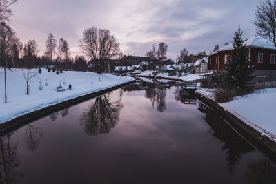 Scenic view of buildings by canal against sky during winter