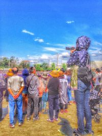 People on field against cloudy sky