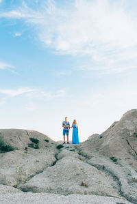 Friends standing on mountain against sky