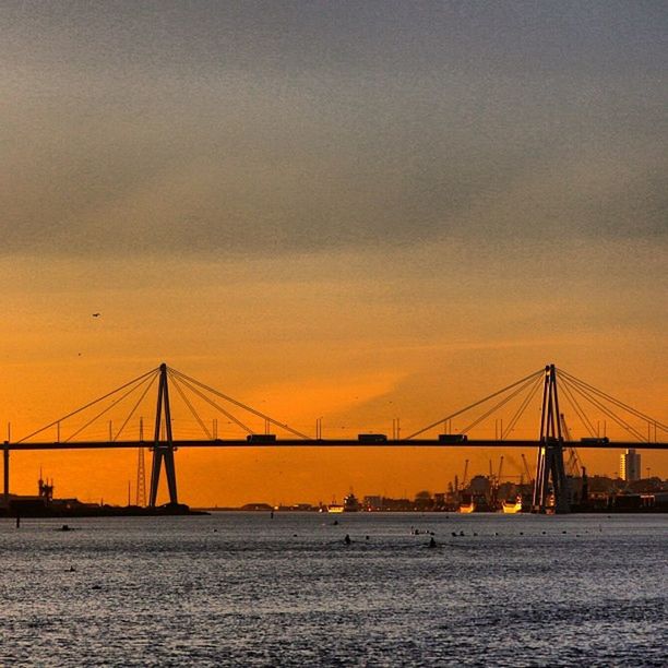 sunset, water, transportation, connection, bridge - man made structure, waterfront, built structure, architecture, sea, suspension bridge, sky, engineering, silhouette, orange color, travel destinations, river, travel, bridge, nature, dusk