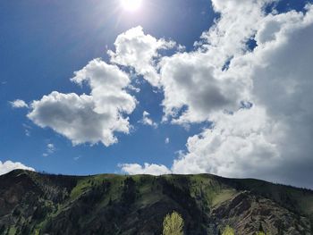 Low angle view of sun shining through clouds