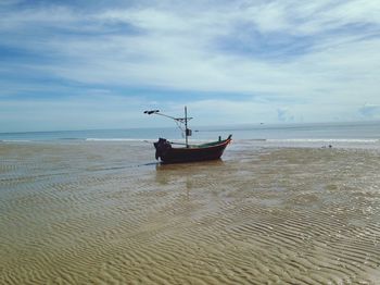 Boat moored on beach against sky