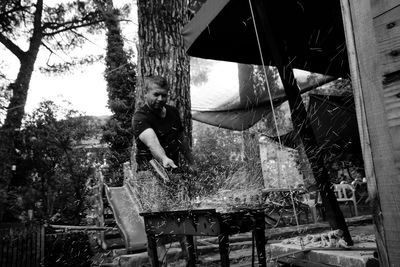 Man standing by barbecue grill with sparks at park