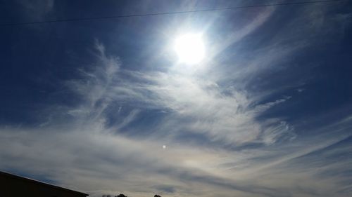 Low angle view of sun shining through clouds