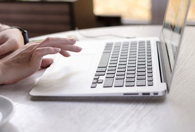 Close-up of woman using laptop on table