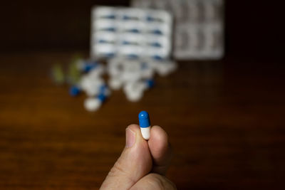 Simple pile of white, blue and yellow pills, medicines, pills stacked on brown background. 