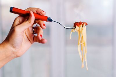 Cropped hand holding fork with pasta