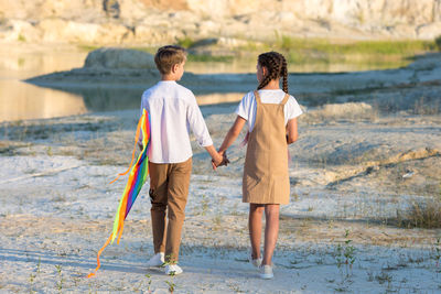 Brother and sister are going to fly a kite chatting sweetly.