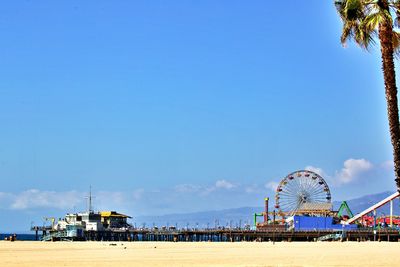 Ferris wheel on beach against clear blue sky