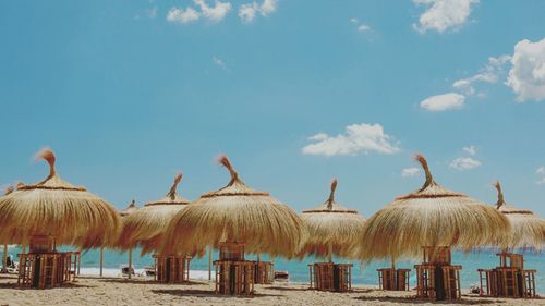 Panoramic shot of parasols on beach against blue sky