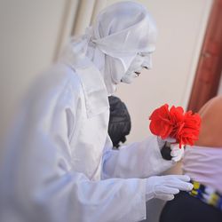 Close-up of woman in costume holding artificial red flower