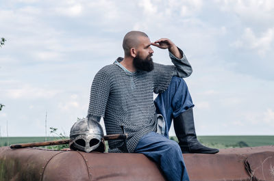 Emotional photo of medieval viking in metal chain mail, looking anxiously into the distance. 