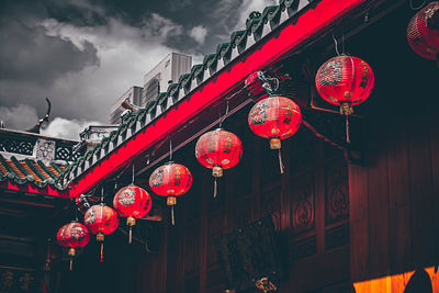 Low angle view of lanterns hanging by building against sky