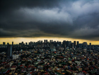 Aerial view of modern buildings in city against storm clouds