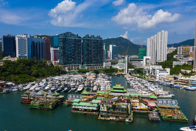 Sailboats moored on harbor by buildings in city against sky