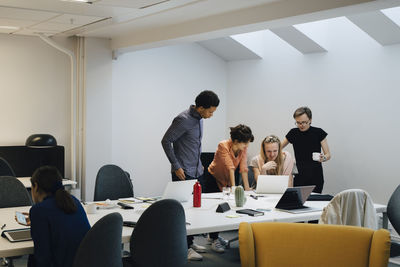 Team of business professionals discussing over laptop in board room during meeting