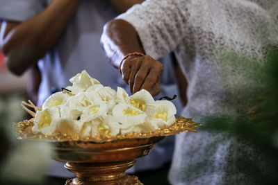 Midsection of woman holding flowers in container