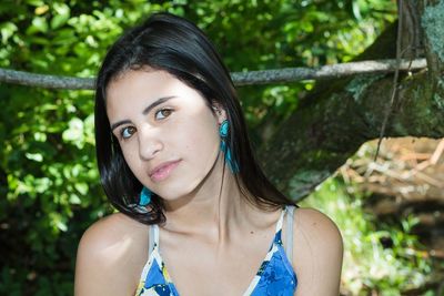 Portrait of young woman standing against tree