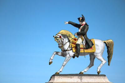 Low angle view of horse sculpture against clear blue sky