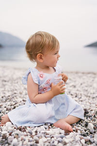 Cute girl sitting on pebbles at beach