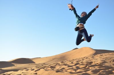 Low angle view of man jumping against clear sky