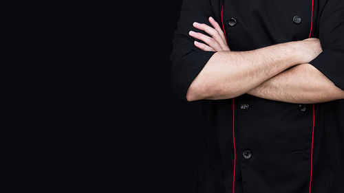 Chef in black jacket standing with arms folded 
