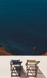 High angle view of chairs in balcony over sea on sunny day