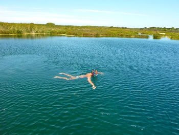 Man swimming in lake against sky