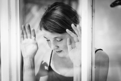 Close-up of young woman with hand on window