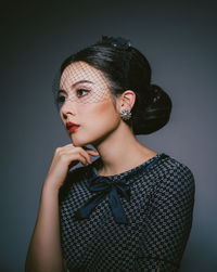 Portrait of young woman against gray background